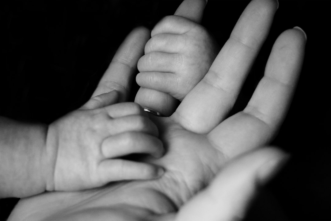 Baby gripping a parent's fingers, a reminder to establish legal parentage early